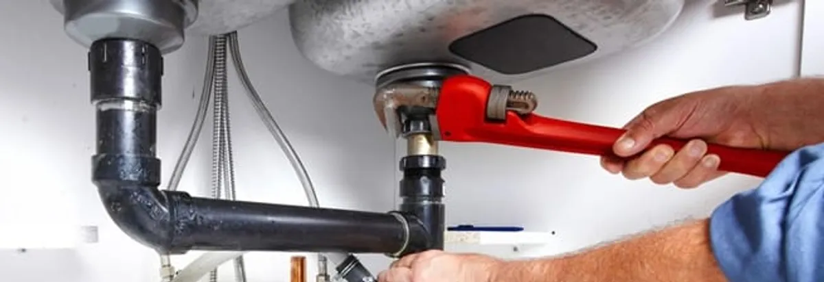 Garbage disposal repair technician tightening the sink drain and disposal connection in Fort Collins, CO