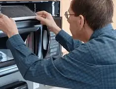 Appliance repair technician replacing a microwave vent filter in Fort Collins, CO