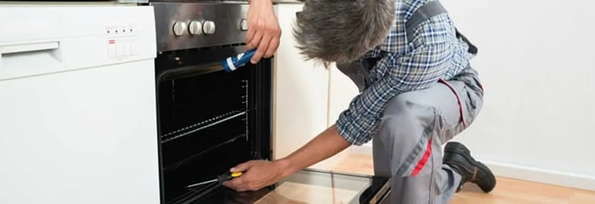 Oven repair technician inspecting and servicing an electric oven in Fort Collins, CO