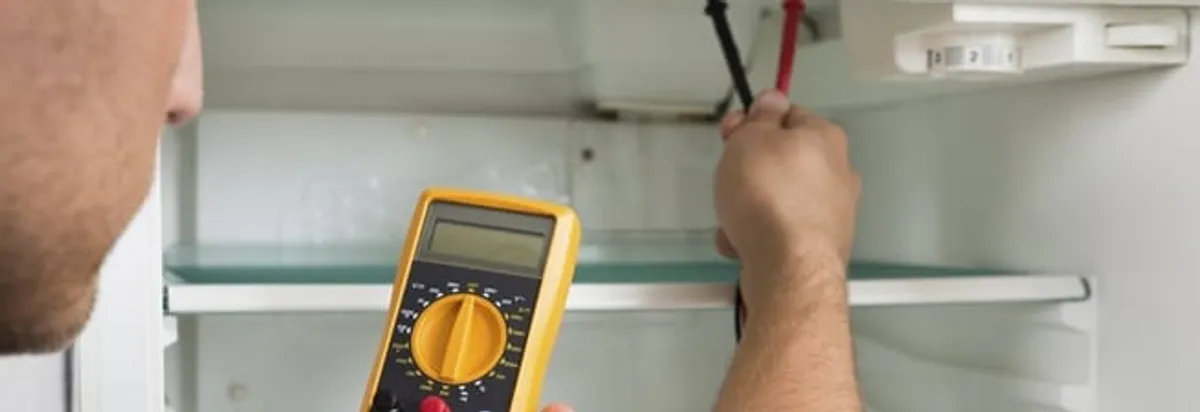 Refrigerator repair technician testing electrical components with a multimeter in Fort Collins, CO