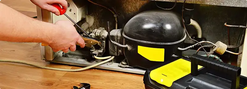 Refrigerator repair technician fixing the compressor and wiring in Fort Collins, CO